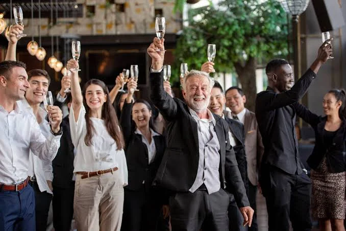 Equipe de empresa erguendo taças em brinde durante confraternização de fim de ano