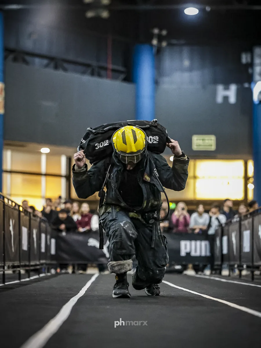 PH Marx fotografando atleta com capacete e sandbag no HYROX em São Paulo
