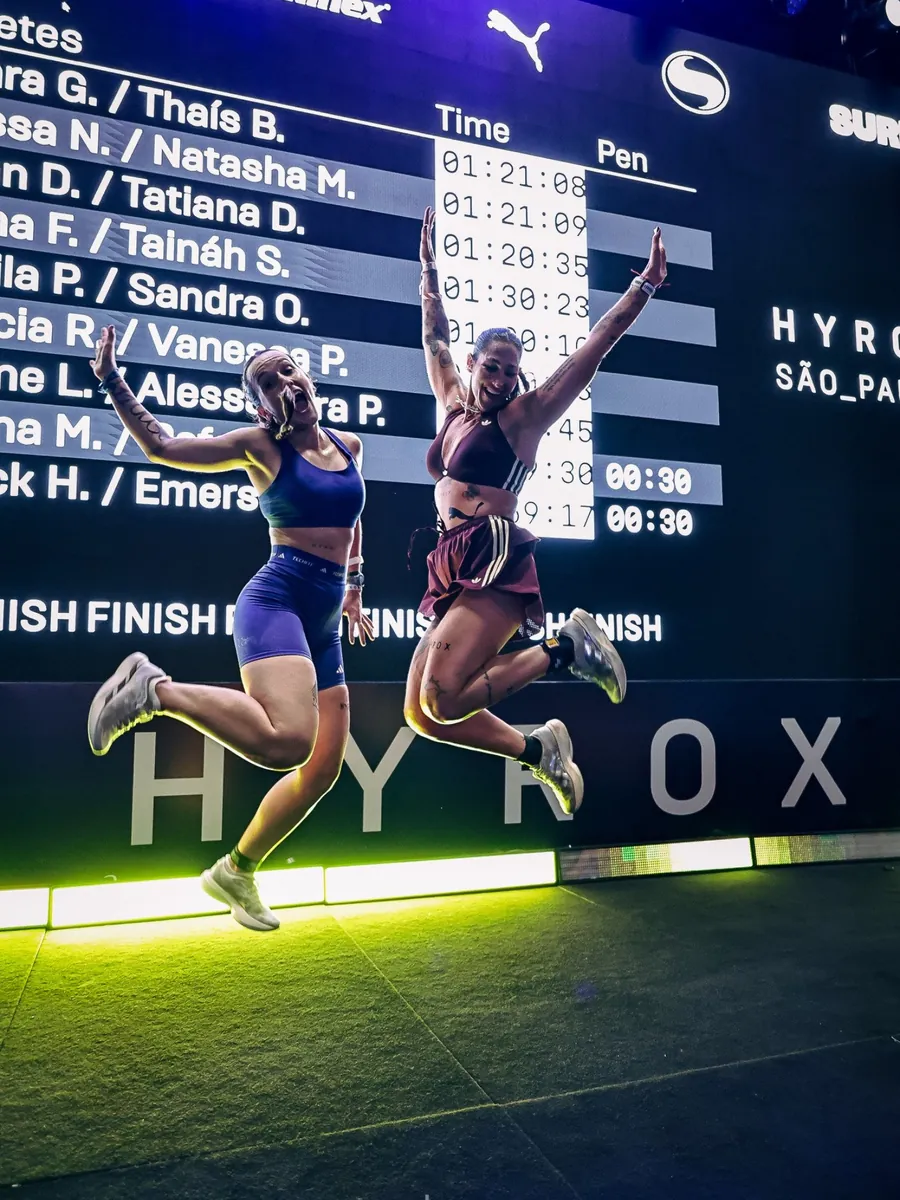 Dupla feminina comemorando na chegada do HYROX São Paulo, foto de PH Marx