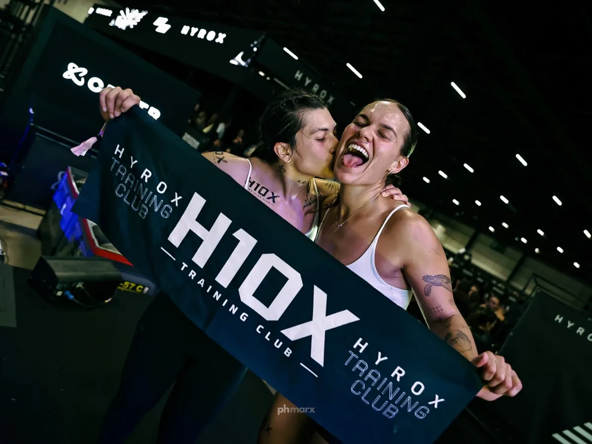 Atletas comemorando com a faixa de um HYROX Training Club, box afiliado, por PH Marx